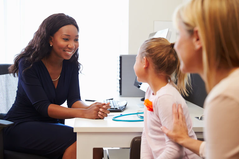 Doctor smiles at child with mum