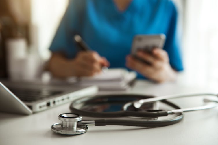 Doctor's stethoscope sits on the desk, next to laptop