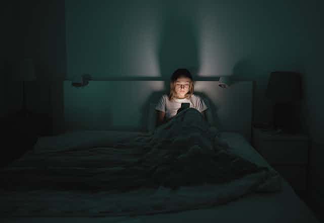 ineffective use of social media case study A medium distance view of a tired woman sitting up at night in her bed looking at a smartphone.