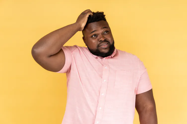 Man wearing pink shirt looking confused