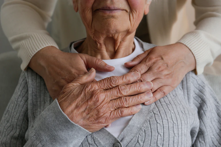 Femme méconnaissable qui s'occupe d'une vieille dame, la serrant dans ses bras derrière la main.