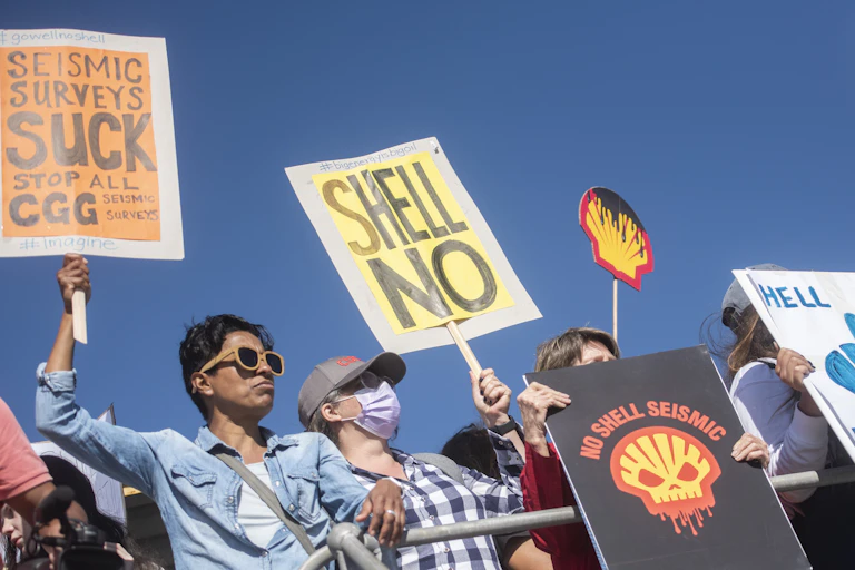 Protesters stand with placards that say 'hell no, Shell must go' and 'no Shell seismic' and 'Seismic surveys suck'