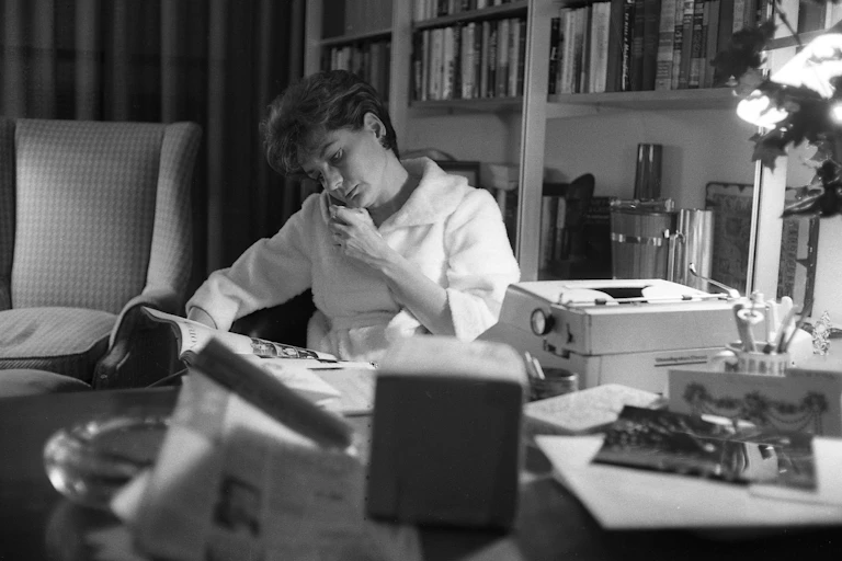 Black and white photo of a young woman on the phone, sitting at her desk.