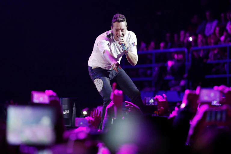 Chris Martin, vocalista do Coldplay, interage com fãs durante um show em Milão