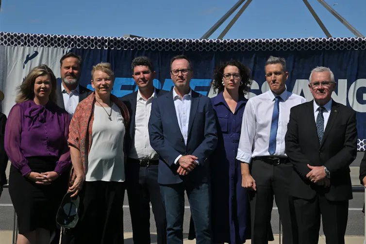 A group of eight people in corporate dress stand outside