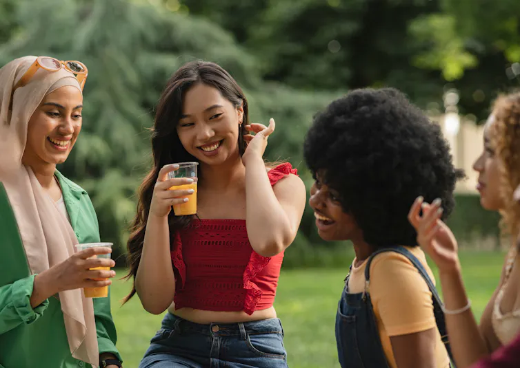 groups of women outside drinking orange juice in cups