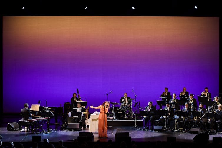 A woman on stage with an orchestra.