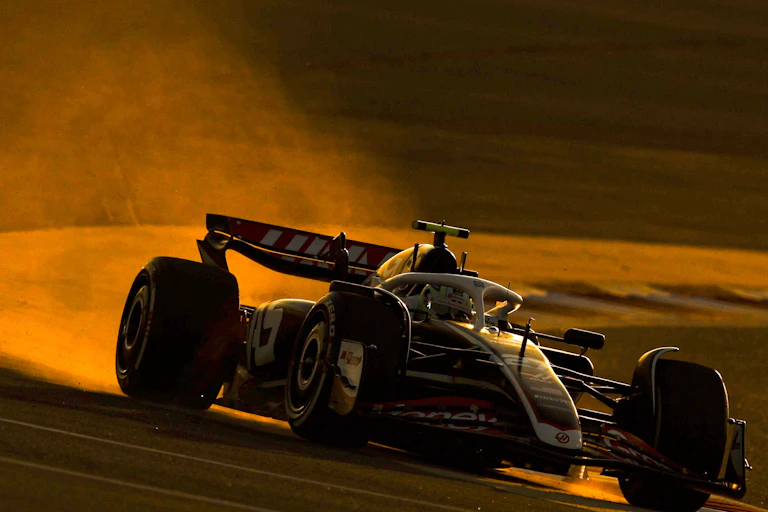 A Formula One car spits out fumes as it turns a corner