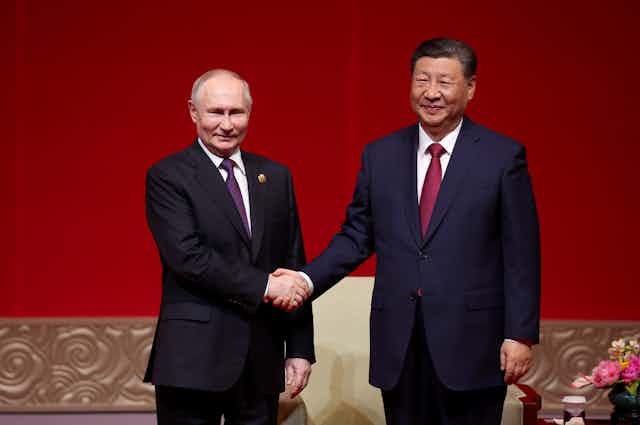 Presidents Putin and Xi shake hands.