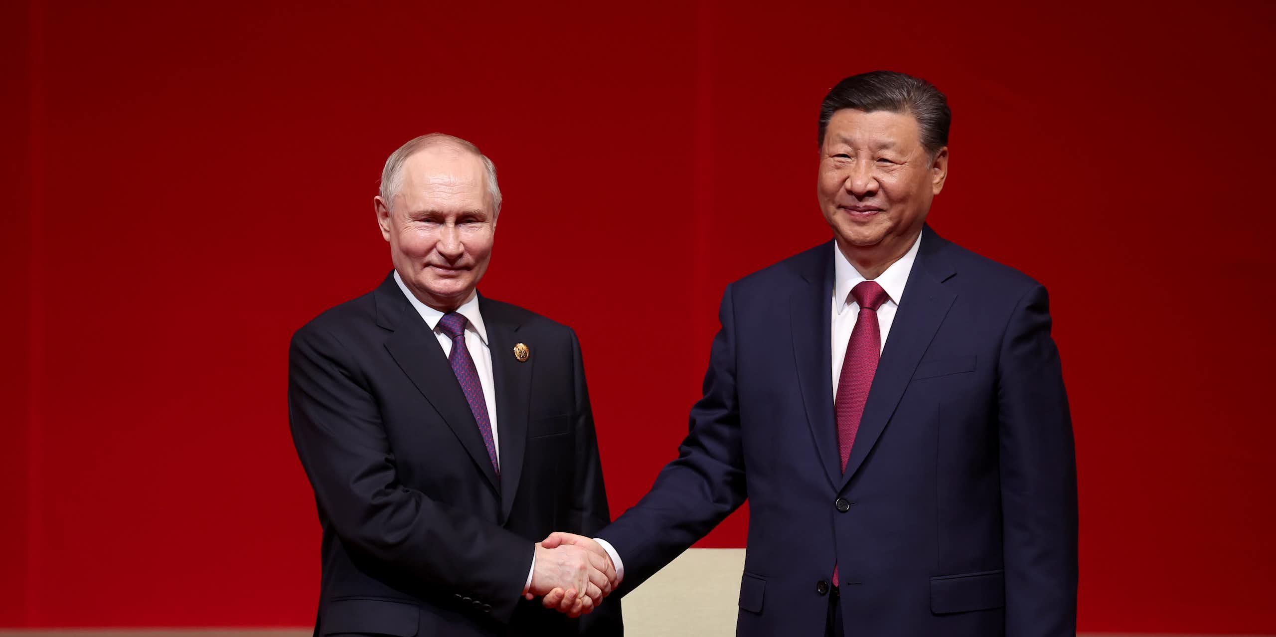 Presidents Putin and Xi shake hands.