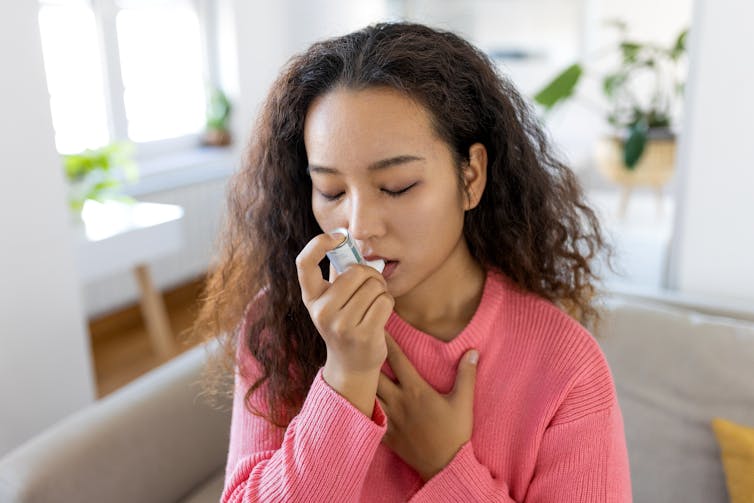 A woman uses an asthma inhaler.