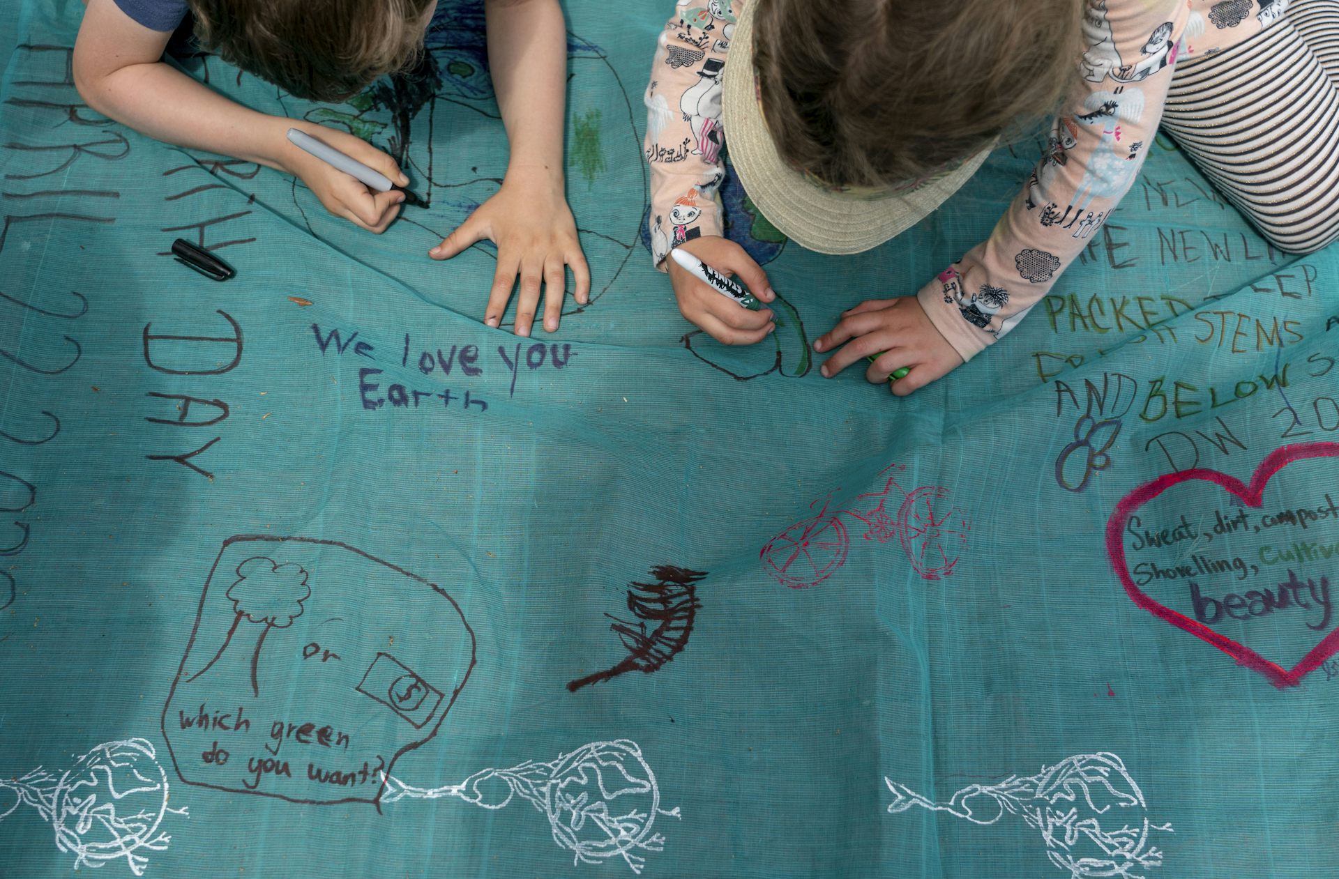 Children write messages on a fabric.