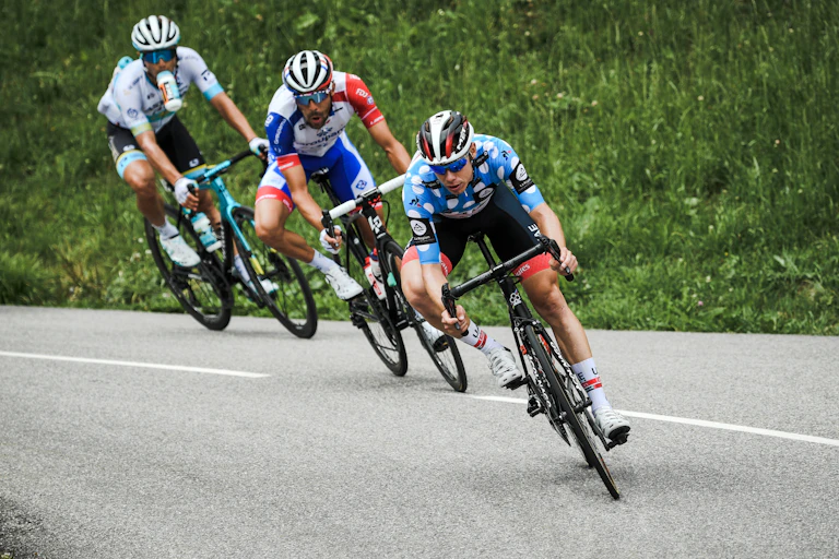 Trois coureurs cyclistes en descente dans un virage lors d'une course.