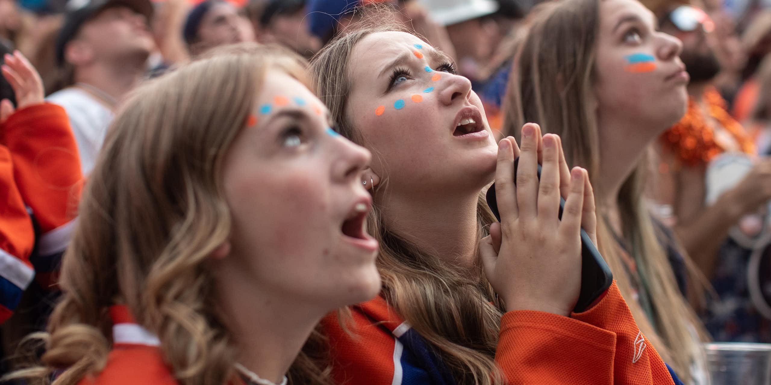 Three women in Edmonton jerseys look up, with one appearing to be praying.