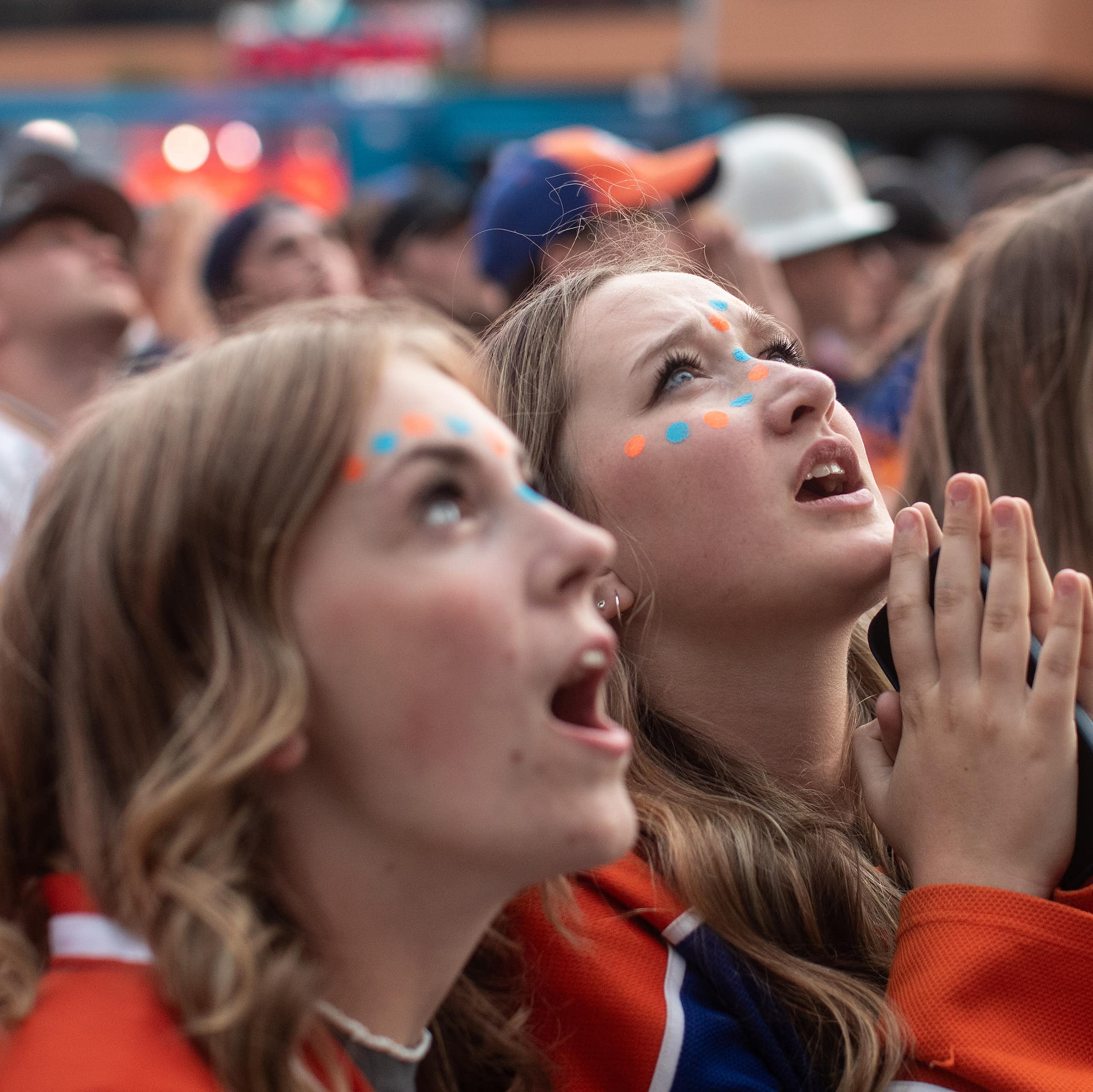 Three women in Edmonton jerseys look up, with one appearing to be praying.