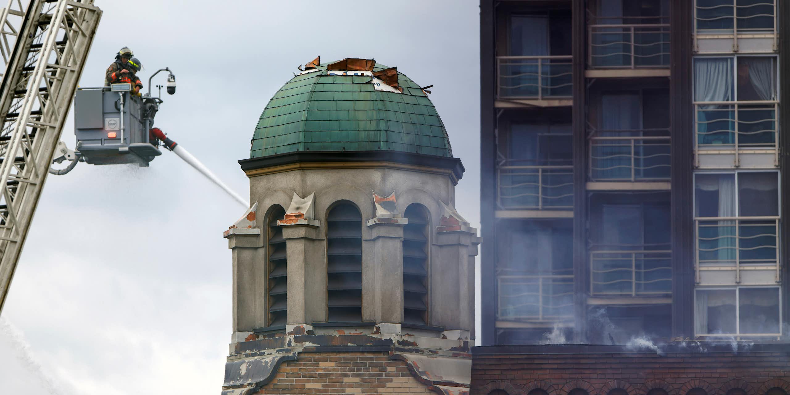 a firefighter on a crane sprays water on a green dome