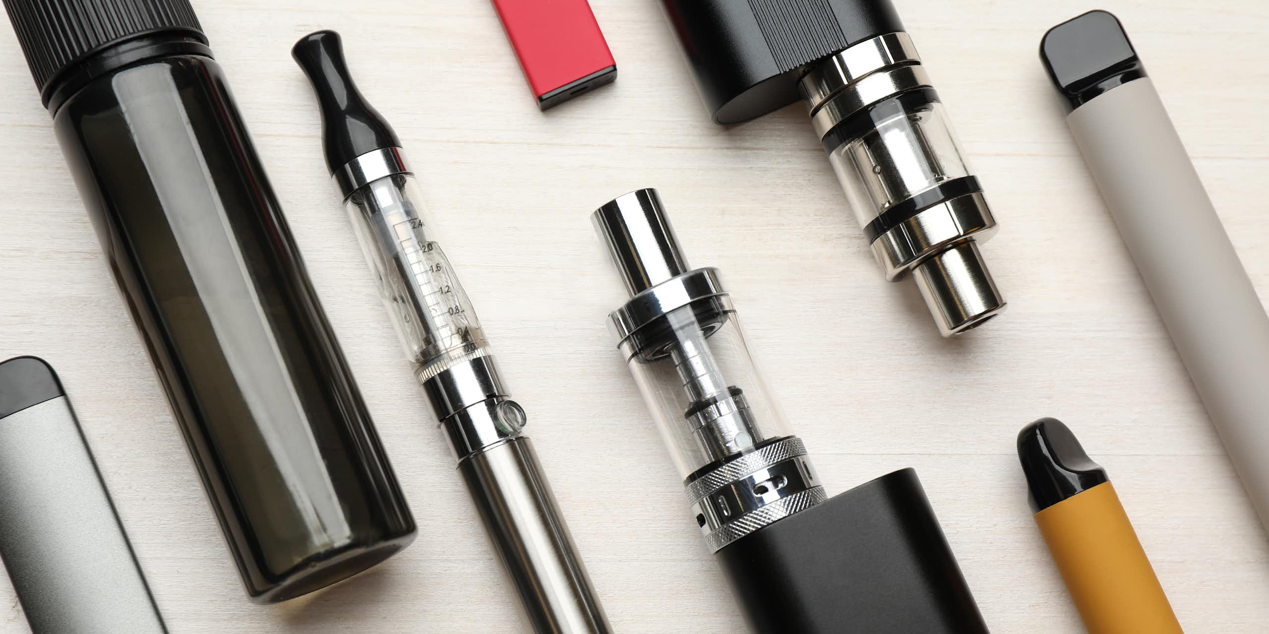 A variety of e-cigarette products lying flat on a white surface.