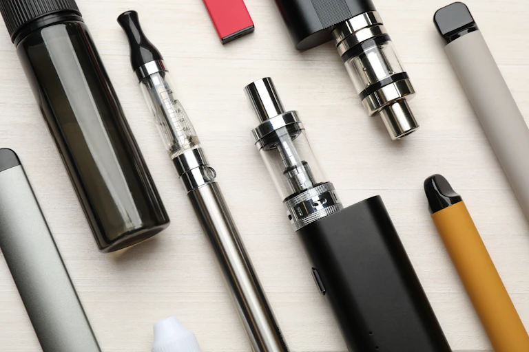 A variety of e-cigarette products lying flat on a white surface.