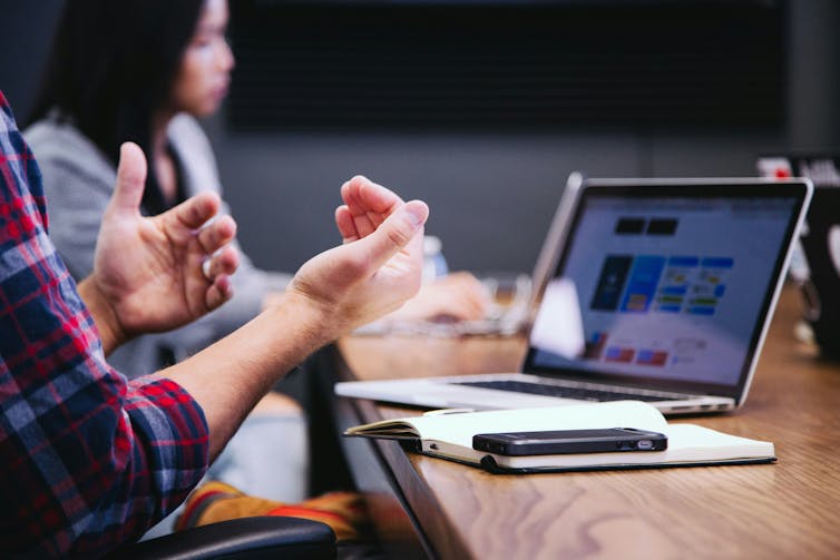 Close up of man gesturing with hands and work laptop screen