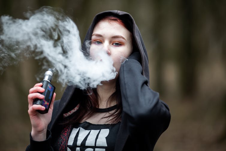 Teenager vaping in the street.
