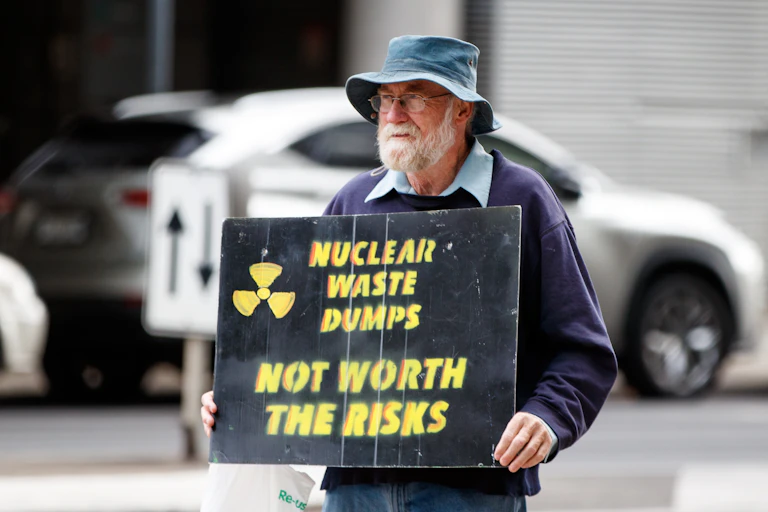 man holds sign saying 'nuclear waste dumps: not worth the risks'