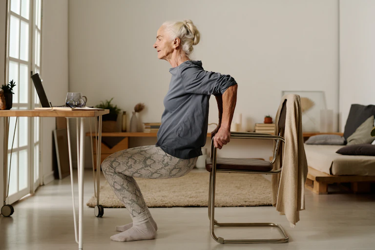 A woman does assisted tricep dips.