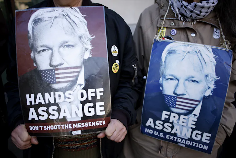 Two posters of a man with a US flag over his mouth saying HANDS OFF ASSANGE