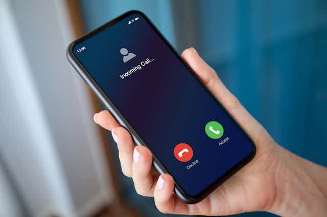 female hand holding phone with incoming call on the screen blue background