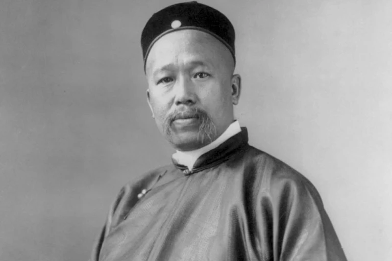 A portrait if a Chinese man with a moustache wearing a hat.