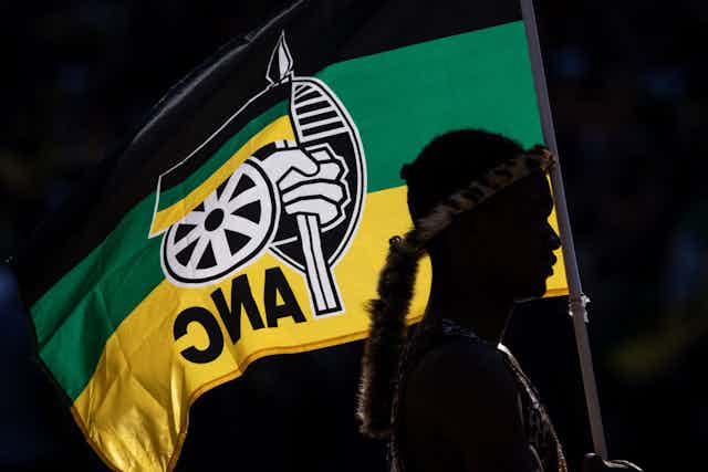 Person silhouetted against black, green and yellow flag 