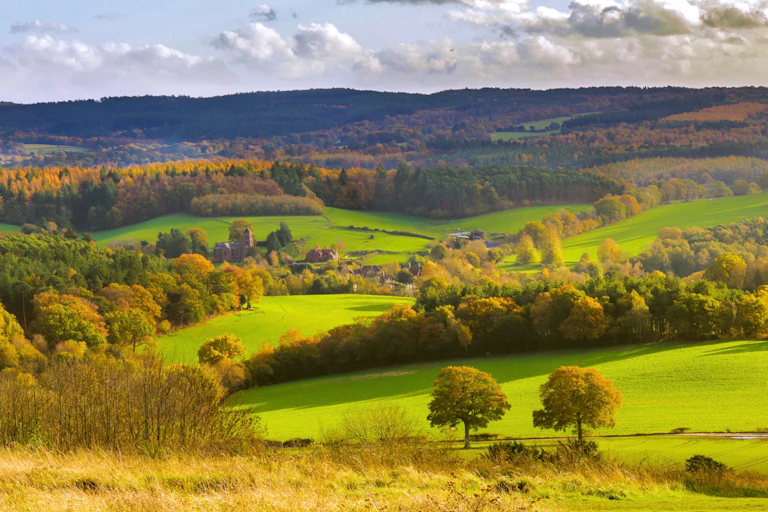 countryside hills, autumn trees and green hills, cloudy sky