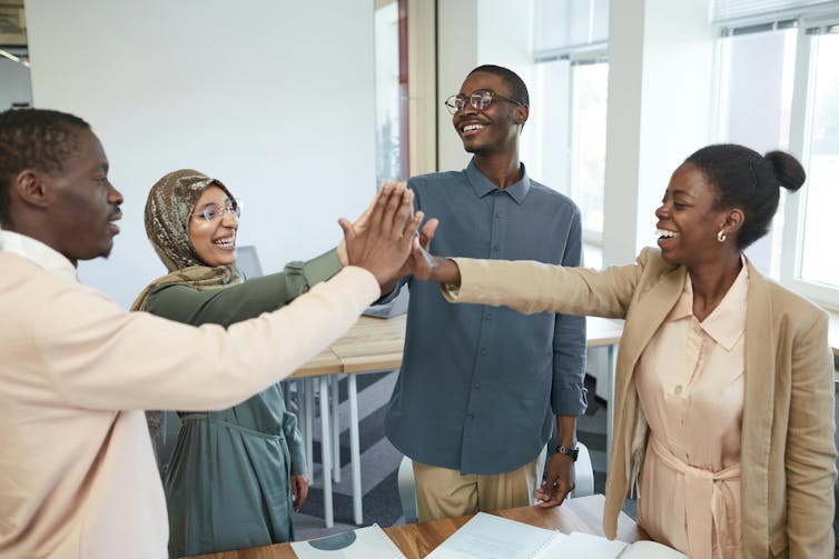 Black people standing in a circle touching palms.