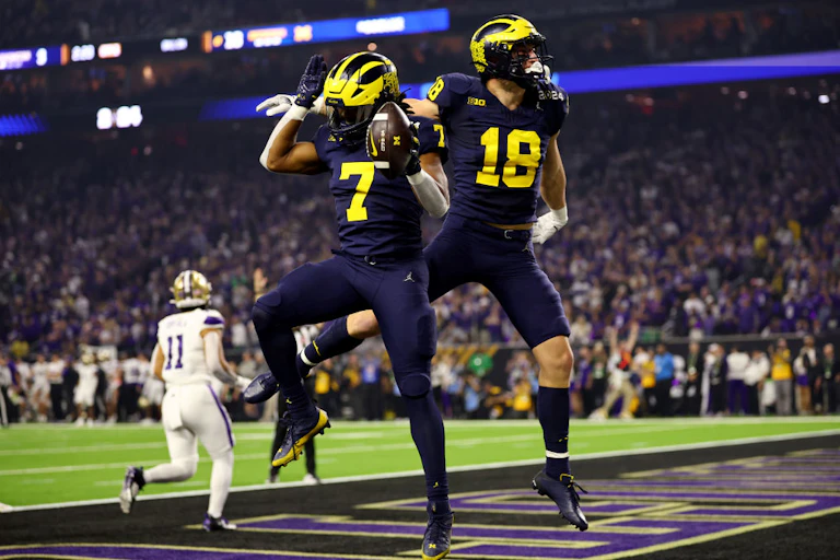 Two football players celebrate in the end zone.