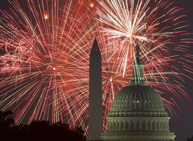 The Washington Monument and U.S. Capitol are seen in silhouette amid a fireworks display.