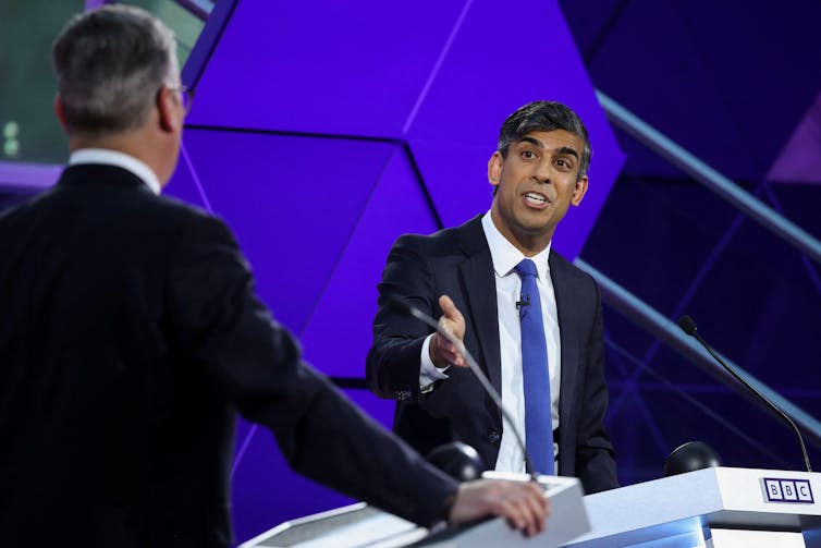 Keir Starmer e Rishi Sunak no pódio de um estúdio de TV.