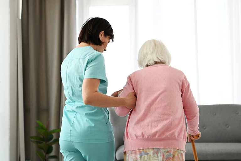 A nurse helps a senior woman move around a room.