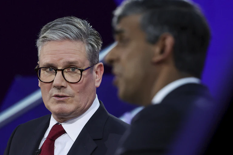 A man with grey hair and glasses looks at another man