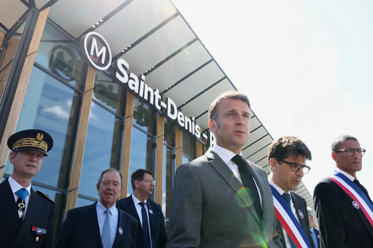 A man in a grey suit leaving a french metro station with other men