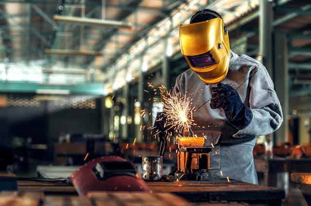 Worker welder working welding steel in industry with safety mask safety gloves and safety equipment