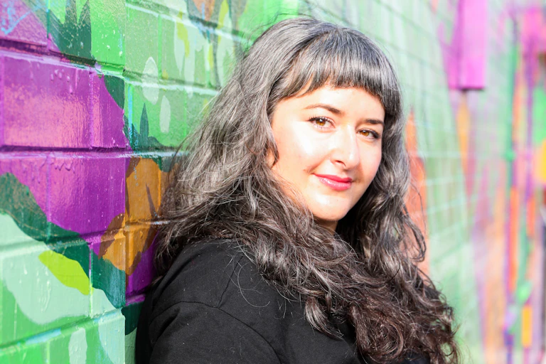 Woman stands in front of wall painted with street art