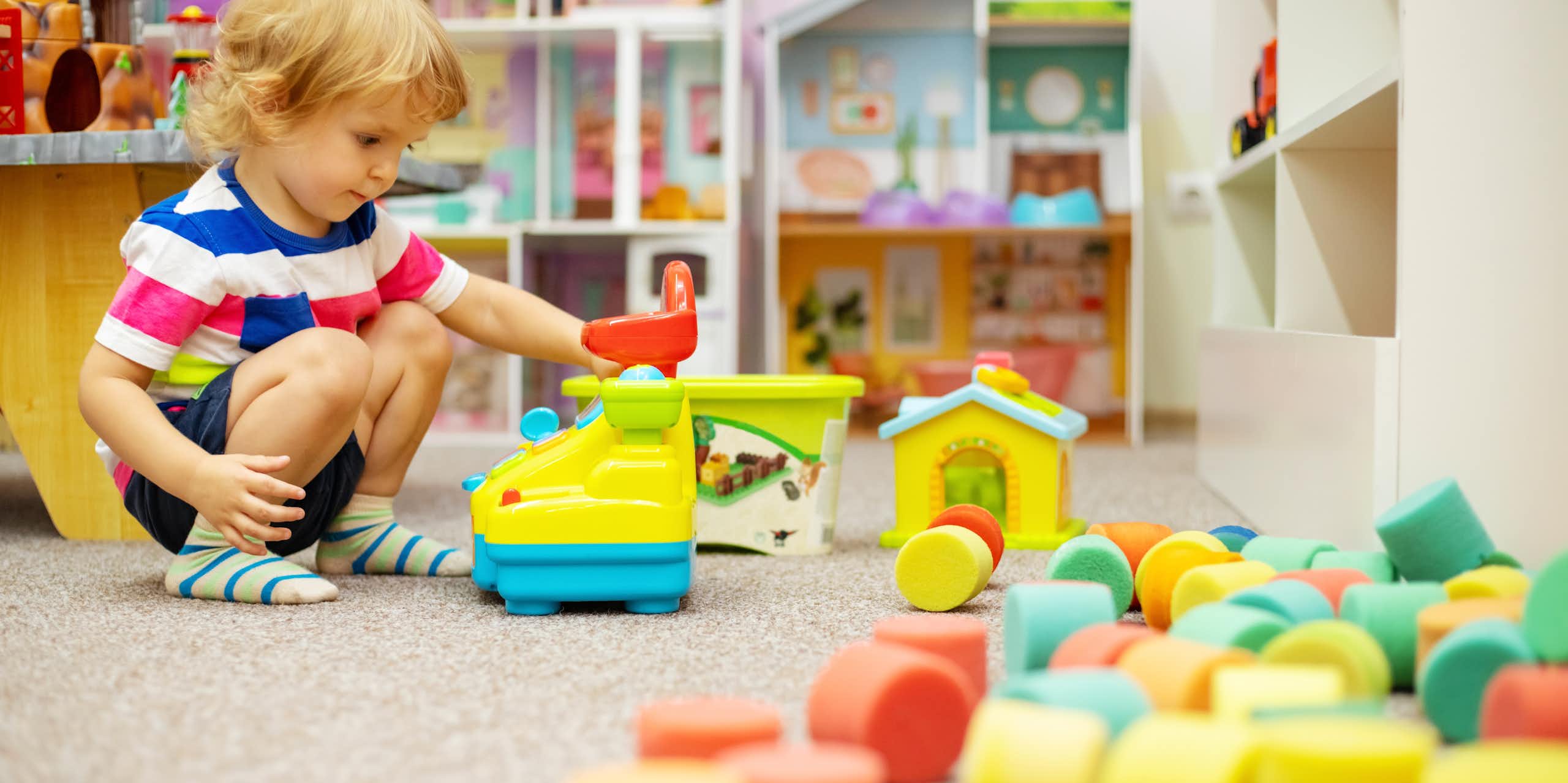 A child plays with soft toys in a nursery setting.