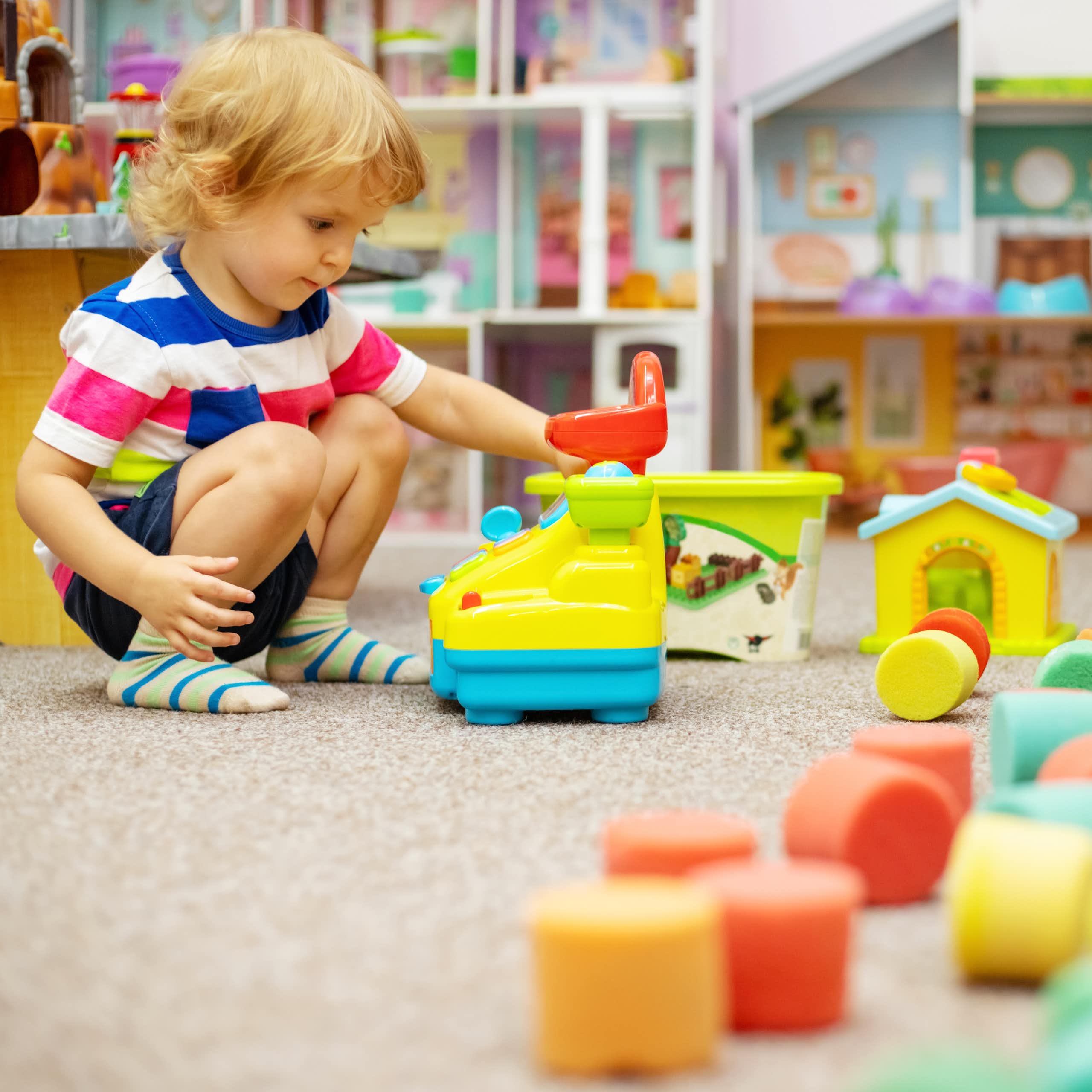 A child plays with soft toys in a nursery setting.