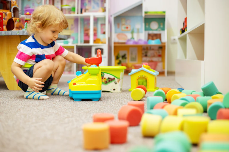 A child plays with soft toys in a nursery setting.