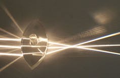 Des rayons lumineux passent à travers une lentille, ce qui déforme leur trajectoire