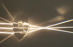 Des rayons lumineux passent à travers une lentille, ce qui déforme leur trajectoire