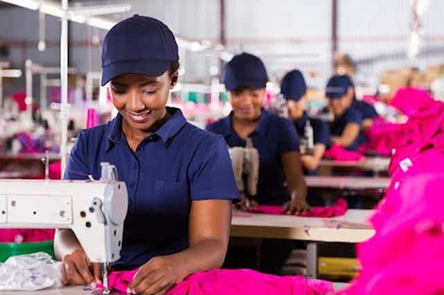 Des travailleurs africains cousant des tissus dans une usine textile