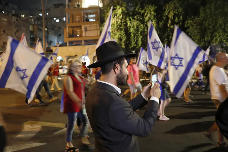An ultra-Orthodox Jewish man films women marching in protest at laws proposed by ultra-Orthodox parties that would affect their rights.