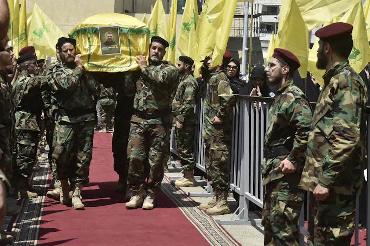 Uniformed Hezbollah fighters carrying a coffin with a guard of homour.