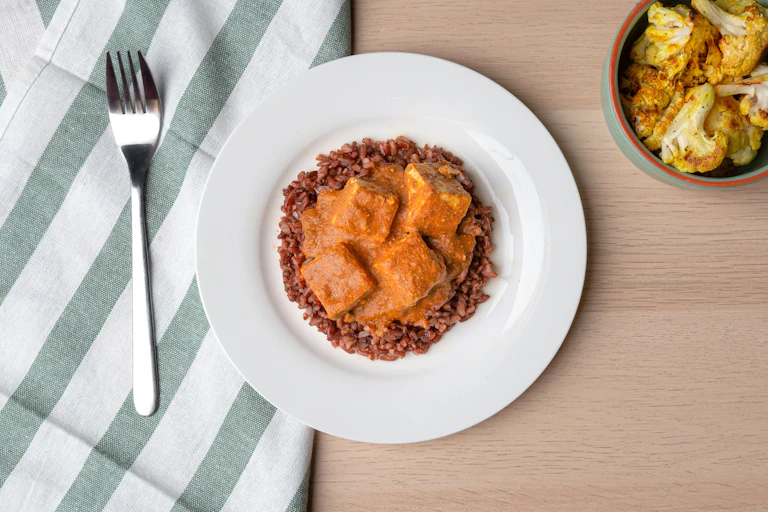 A plate of tofu and rice is pictured on a table.