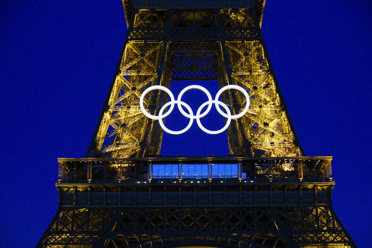 Five white rings in the space between two golden pillars set against a deep blue background.